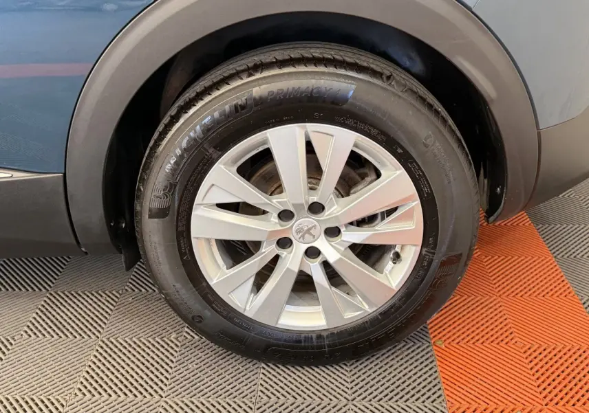 Gros plan sur la roue avant gauche du Peugeot 3008 bleu, avec jante alliage argentée et pneu Michelin Primacy 4.
