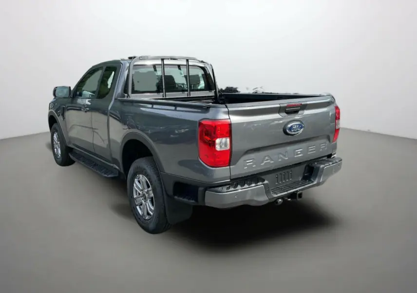 Ford Ranger gris carbone vu en 3/4 arrière droit, avec benne ouverte et barre de protection arrière visible.