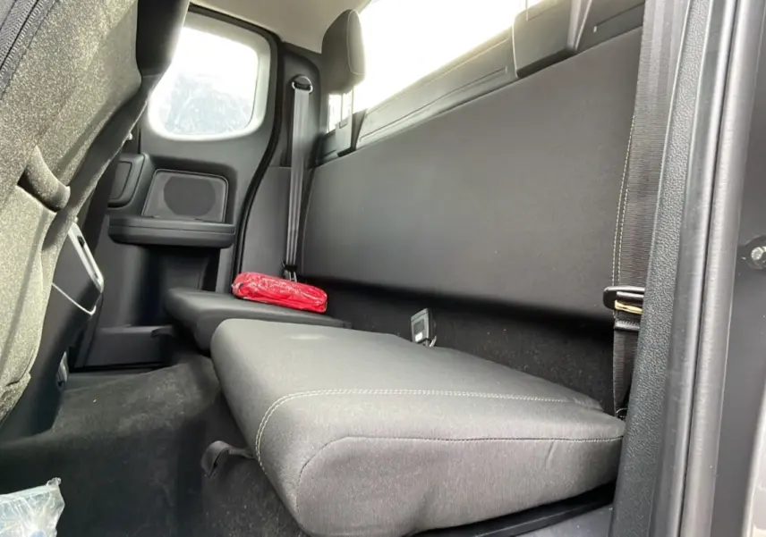 Vue intérieure côté droit sur la banquette arrière noire du Ford Ranger gris carbone avec un sac rouge posé dessus.
