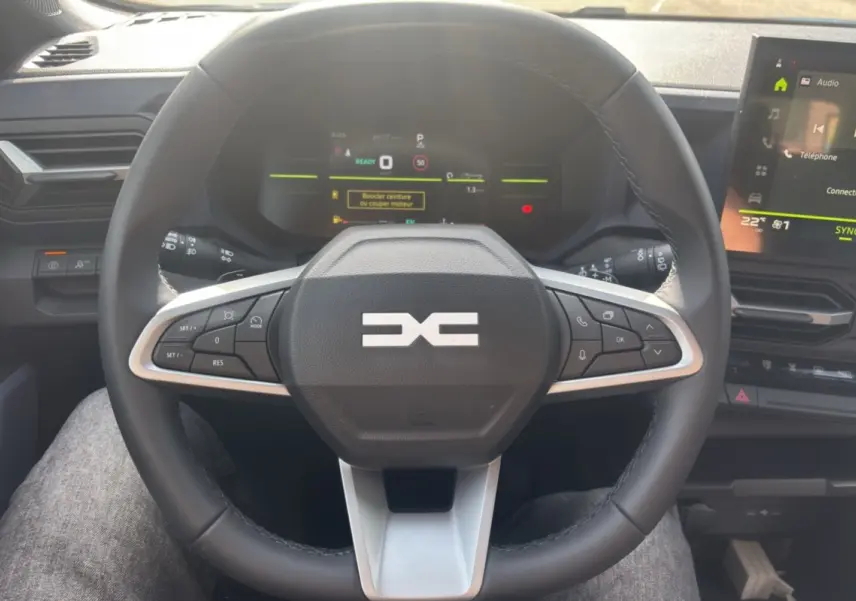 Vue intérieure centrée sur le volant cuir du Dacia Bigster Hybrid-G 150 avec tableau de bord numérique et écran tactile.
