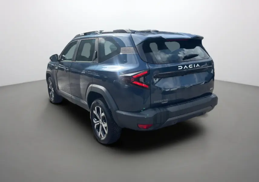 Vue 3/4 arrière droite d'un Dacia Bigster bleu indigo avec barres de toit et jantes alu 17 pouces.