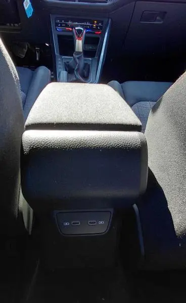 Vue intérieure centrée sur l'accoudoir central et la console avant d'une Volkswagen Polo GTI noire 2024 avec levier de vitesse automatique.