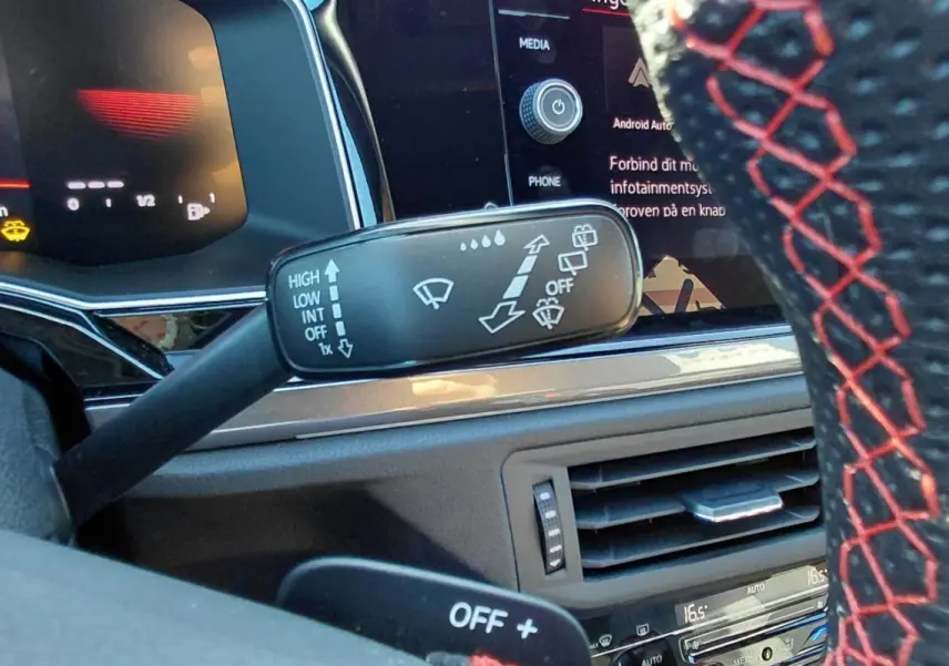 Gros plan sur le commodo d’essuie-glace et volant sport noir avec surpiqûres rouges dans l’habitacle d’une Volkswagen Polo GTI 2024.