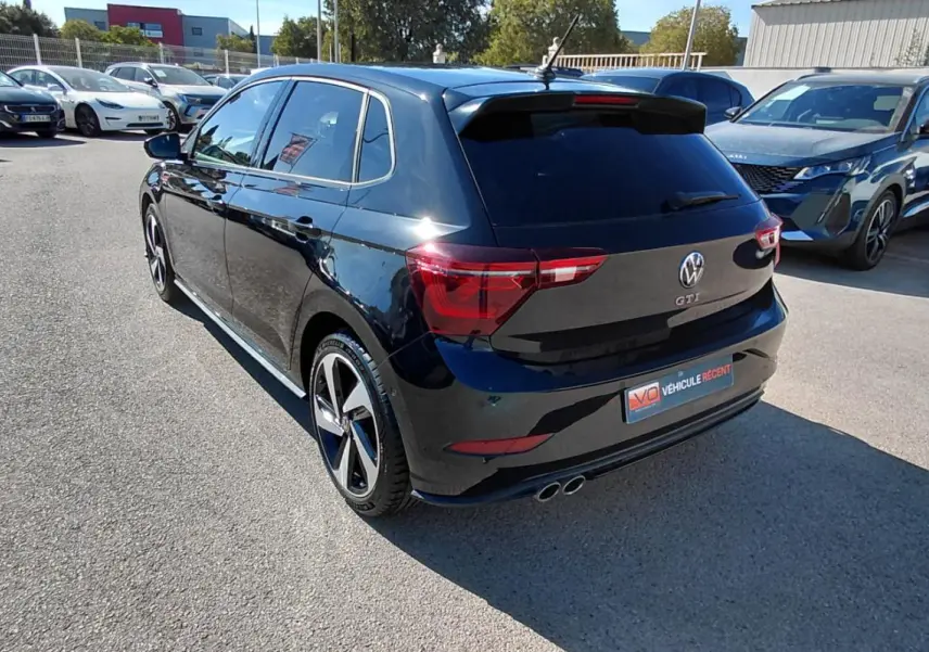 Vue 3/4 arrière droite d'une Volkswagen Polo GTI noire 2024 avec jantes alliage 17 pouces et double sortie d'échappement.