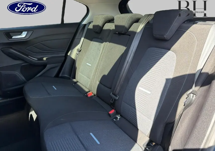 Vue latérale intérieure montrant la banquette arrière noire avec appuie-têtes et ceintures de sécurité grises d'une Ford Focus.