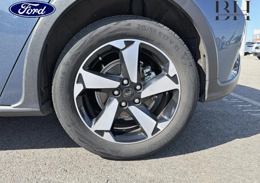 Gros plan sur la roue avant droite de la Ford Focus bleu azur métallisé avec jante alliage bicolore.