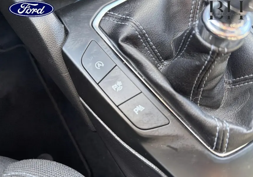 Gros plan sur la console centrale de la Ford Focus 2022 avec levier de vitesse manuel et boutons de contrôle noirs.
