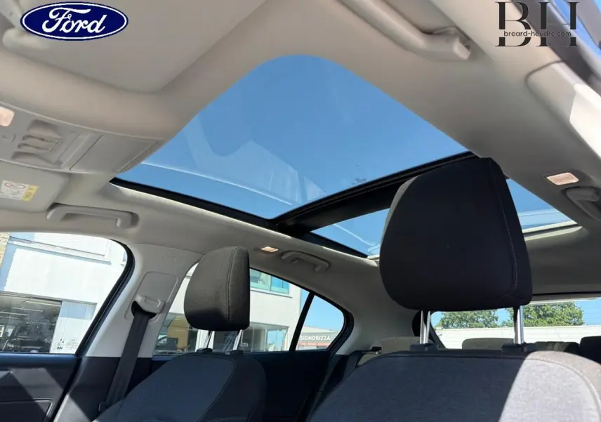 Vue intérieure de la Ford Focus 2022 avec toit panoramique ouvrant et sièges tissu noir côté gauche.