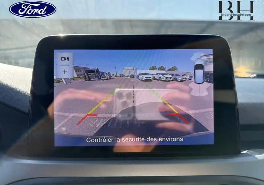 Écran tactile de la caméra de recul de la Ford Focus bleu azur, vue intérieure du tableau de bord en lumière naturelle.