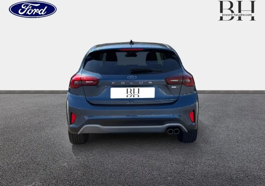 Vue arrière d'une Ford Focus 1.0 Flexifuel bleu azur métallisé avec double sortie d'échappement et vitres arrière surteintées.