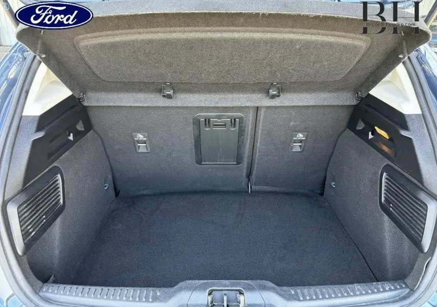Coffre ouvert vu de l'arrière de la Ford Focus bleu azur métallisé, montrant un espace de chargement propre et bien agencé.