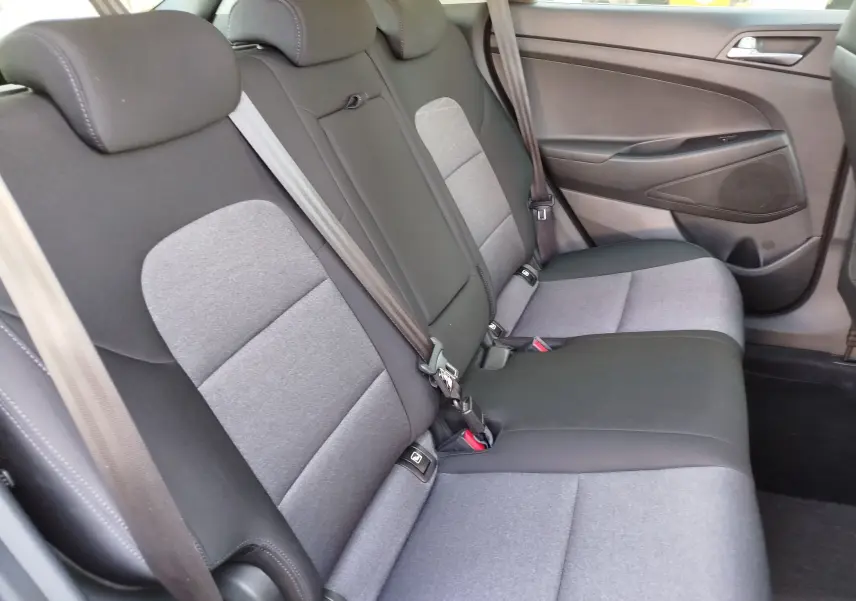Vue latérale droite des sièges arrière gris clair et foncé du Hyundai Tucson 2019, avec ceintures de sécurité visibles.