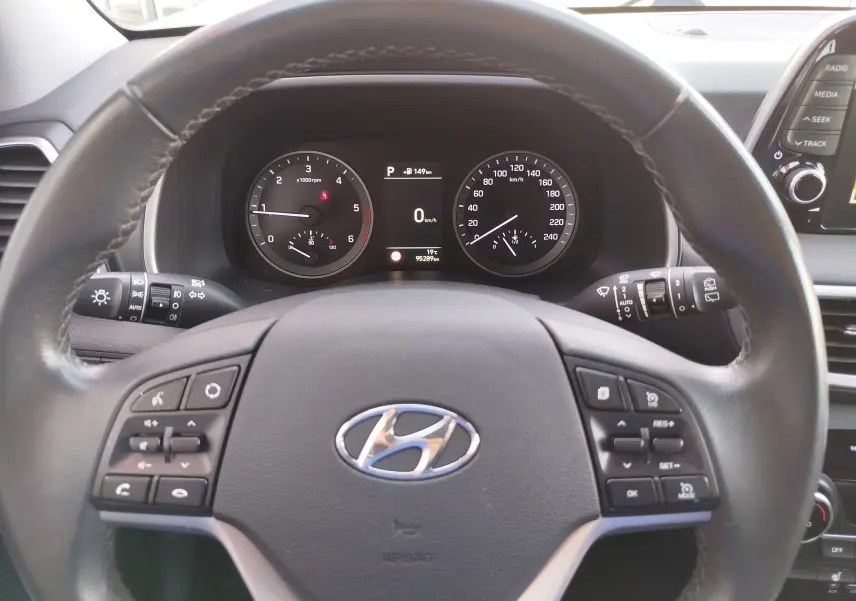 Vue intérieure centrée sur le volant cuir noir du Hyundai Tucson 2019 avec tableau de bord et commandes au volant visibles.