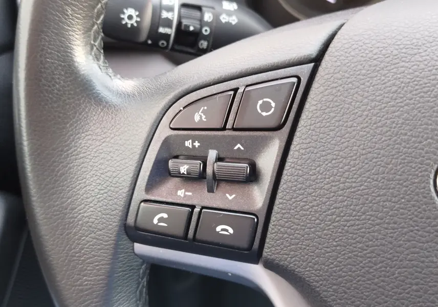 Gros plan sur les commandes du volant en cuir noir du Hyundai Tucson 2019, avec boutons de volume et appels.