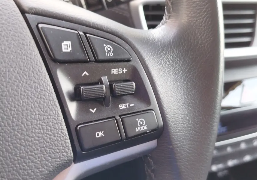 Gros plan sur les commandes au volant côté gauche du Hyundai Tucson 2019, cuir noir et boutons de régulateur de vitesse.