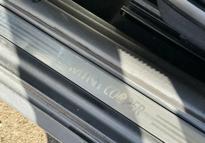 Gros plan sur la plaque de seuil de porte MINI Cooper en métal brossé, avec inscription gravée visible.