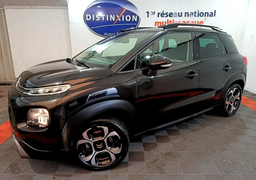 Citroën C3 Aircross noir vue 3/4 avant droit, avec jantes distinctives et barres de toit noires visibles.
