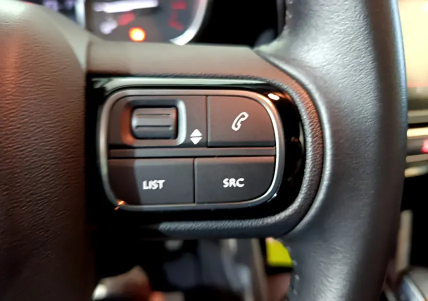 Gros plan sur les commandes gauche du volant cuir noir du Citroën C3 Aircross 2019, boutons LIST et SRC visibles.