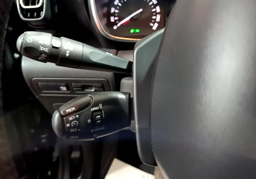 Gros plan côté gauche du volant cuir du Citroën C3 Aircross noir, avec commandes de régulateur et feux visibles.