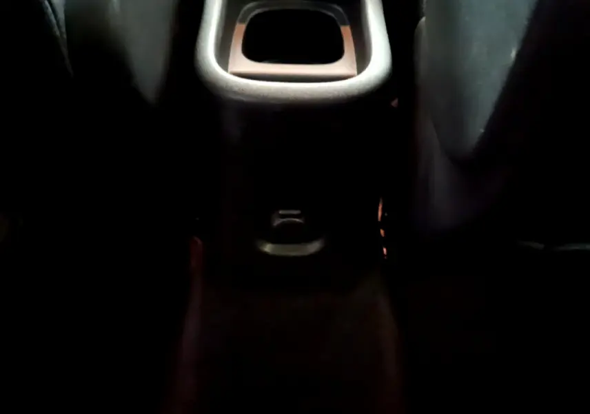 Vue rapprochée de la console centrale arrière noire du Citroën C3 Aircross, avec prise 12V visible entre les sièges arrière.