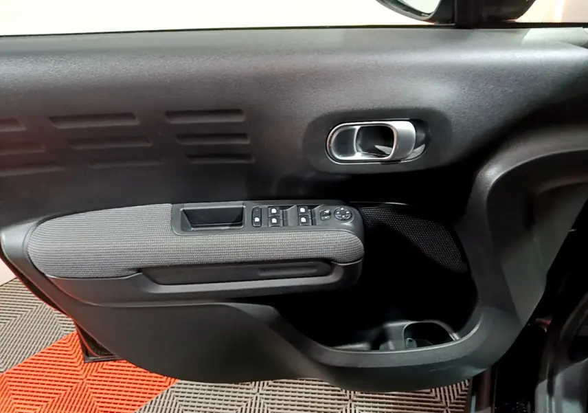 Gros plan sur la porte côté gauche noire du Citroën C3 Aircross 2019 avec commandes de vitres et poignée chrome.
