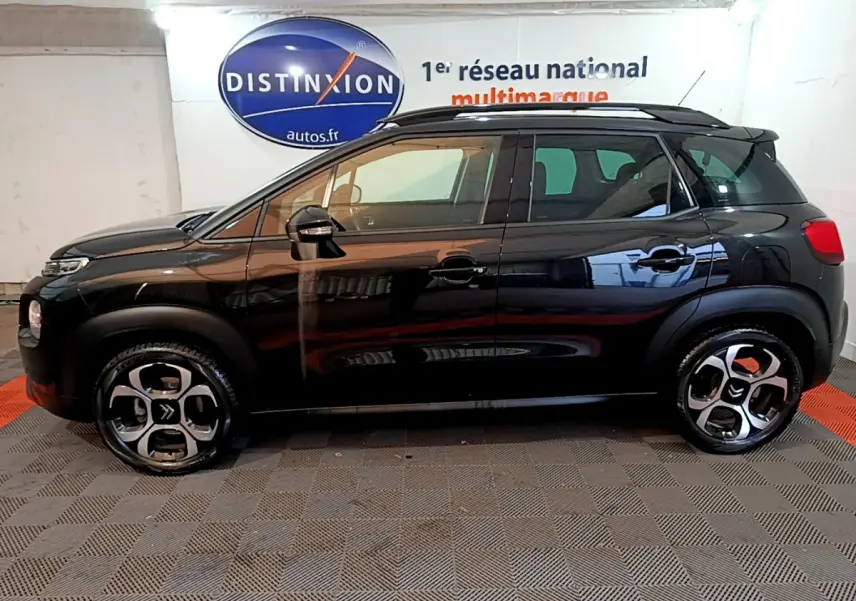 Profil côté gauche d'un Citroën C3 Aircross noir 2019 avec jantes originales et barres de toit noires.