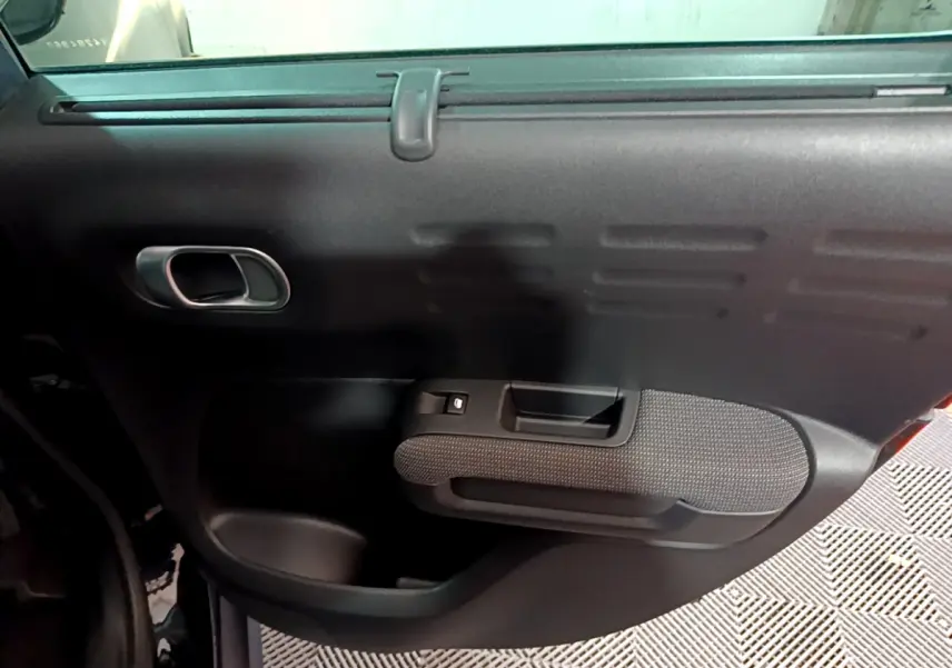 Porte intérieure côté gauche noire de la Citroën C3 Aircross PureTech 110 Shine, avec poignée et commande de vitre.