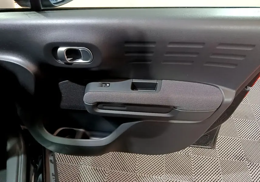 Gros plan sur la porte intérieure côté gauche noire du Citroën C3 Aircross avec poignée et accoudoir tissu.