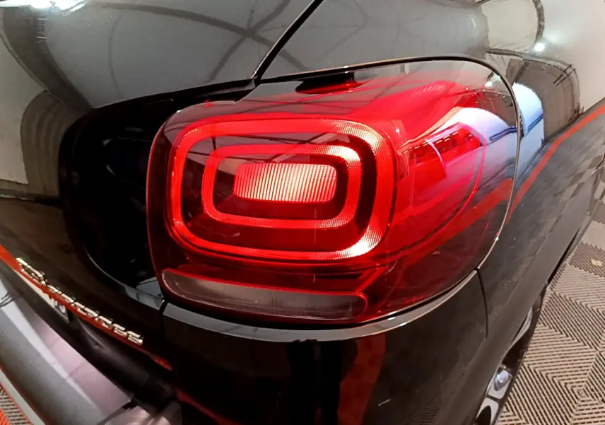 Gros plan sur le feu arrière droit rouge d'un Citroën C3 Aircross noir, avec reflet de l'environnement intérieur.