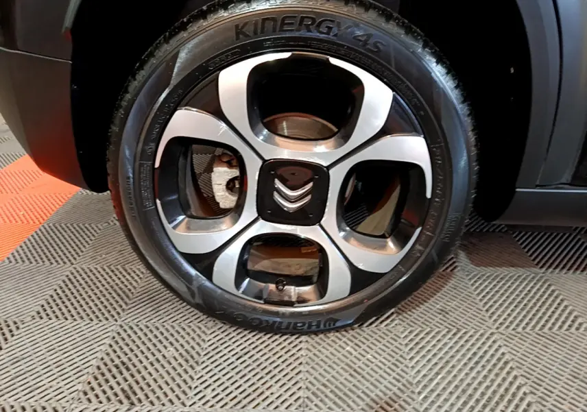 Gros plan sur la roue avant gauche noire du Citroën C3 Aircross avec jante alliage bicolore et logo Citroën central.