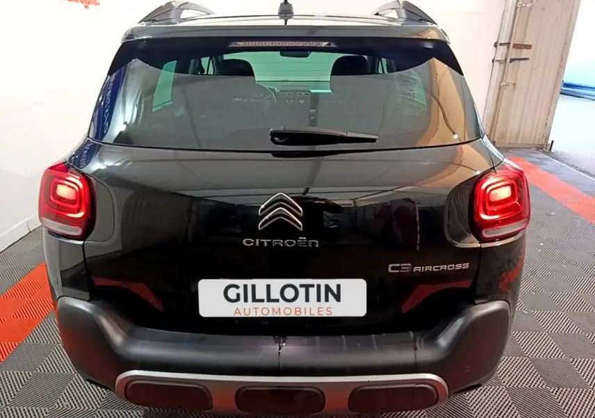 Vue arrière d'un Citroën C3 Aircross noir avec feux allumés et logo visible sur fond intérieur showroom.