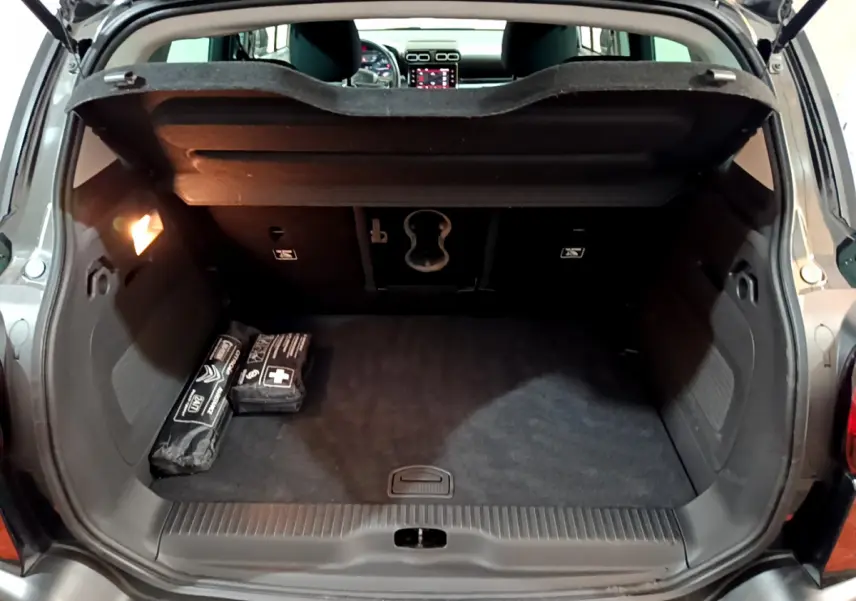 Coffre noir ouvert du Citroën C3 Aircross 2019, vue arrière avec trappe à ski et objets de sécurité posés.