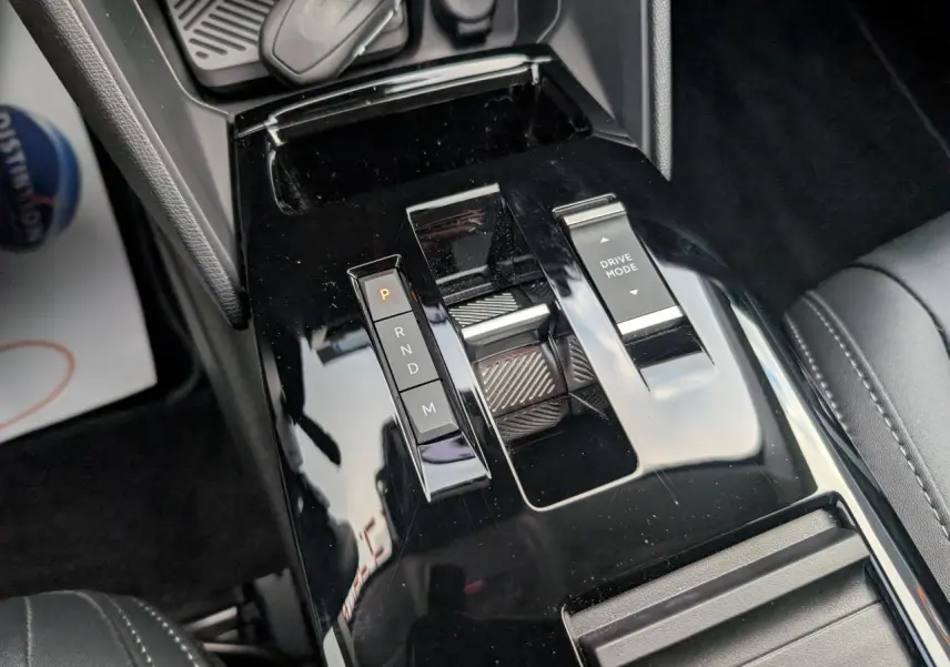 Gros plan sur la console centrale noire brillante de la Citroën C4 2025, avec commandes de boîte auto et mode de conduite.