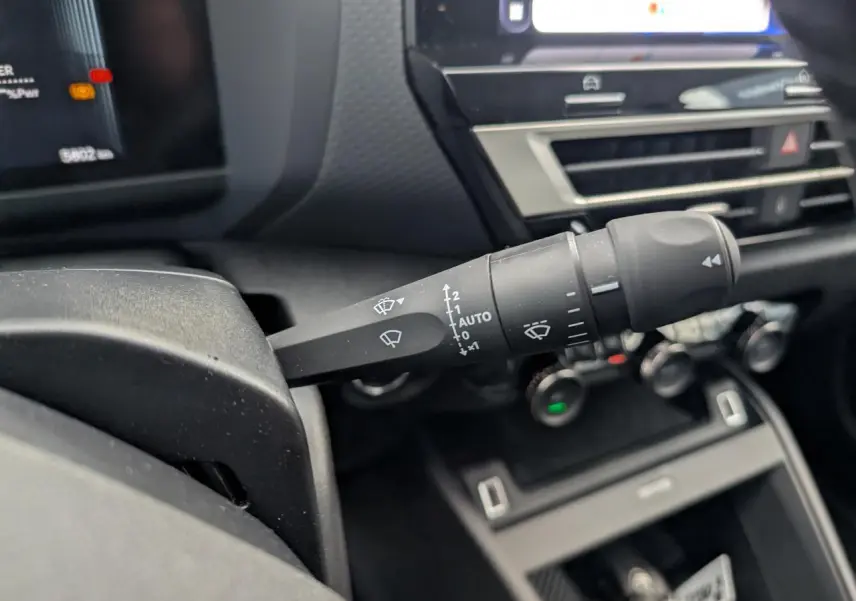 Gros plan sur la commande d'essuie-glace à gauche du volant dans l'habitacle de la Citroën C4 blanche 2025.