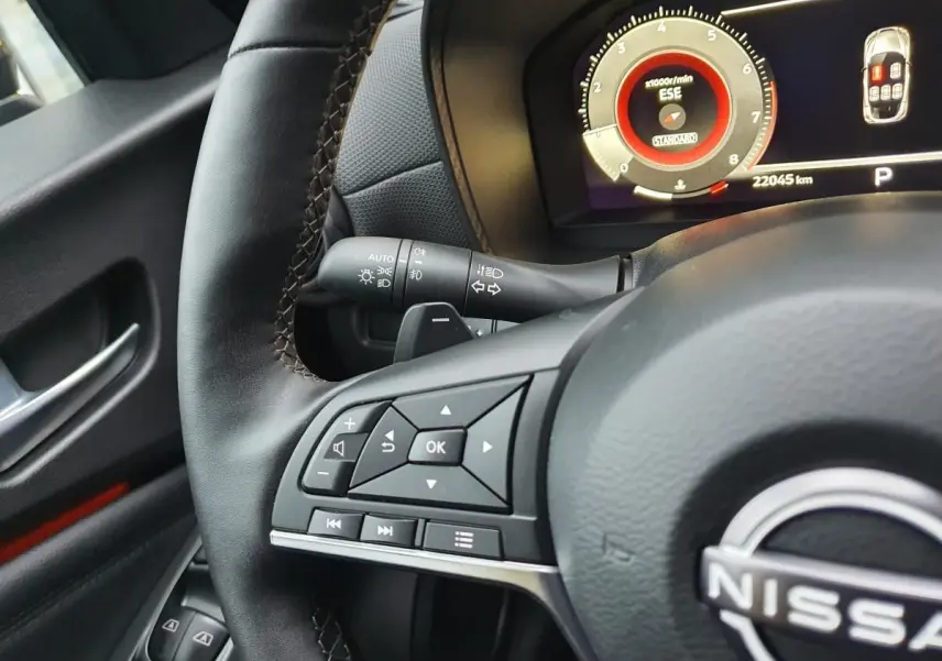 Vue rapprochée du volant noir et du tableau de bord digital du Nissan Juke 2025 avec commandes multifonctions.