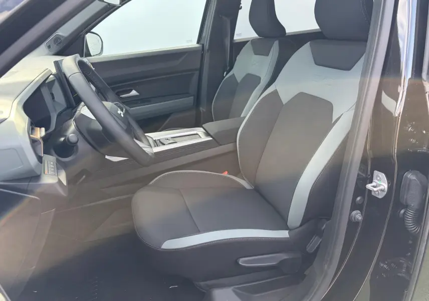 Vue intérieure côté conducteur du Dacia Bigster noir, mettant en valeur les sièges avant bicolores et le volant multifonction.
