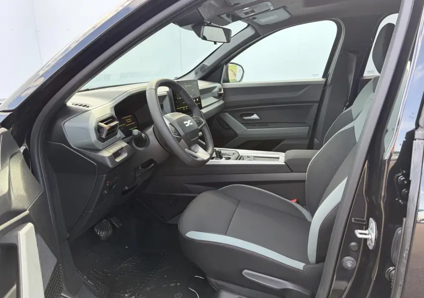 Vue intérieure côté conducteur du Dacia Bigster noir avec sellerie bicolore et tableau de bord moderne.