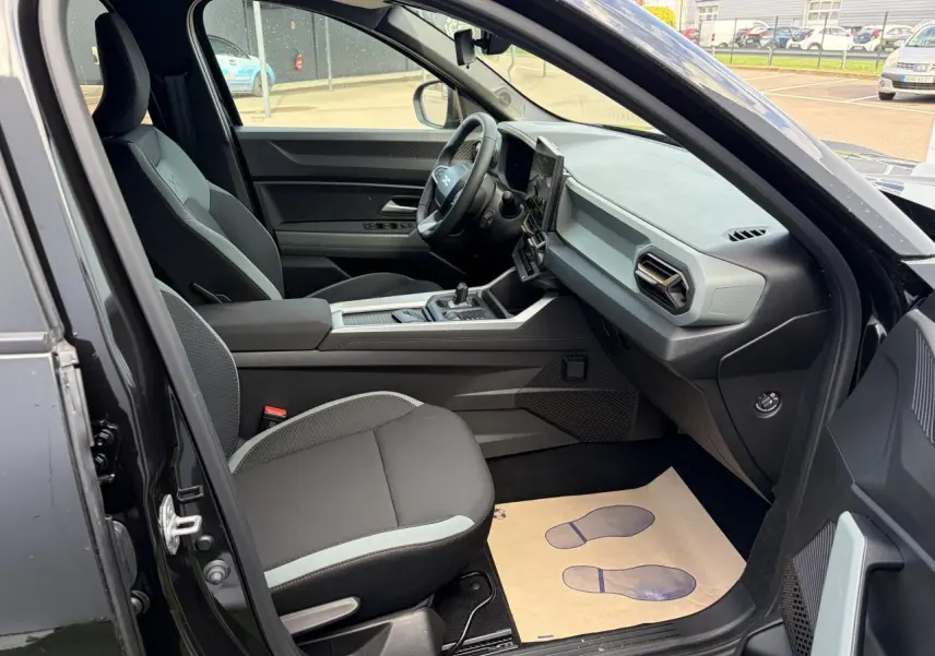 Vue intérieure côté conducteur du Dacia Bigster noir, mettant en valeur les sièges et la console centrale moderne.