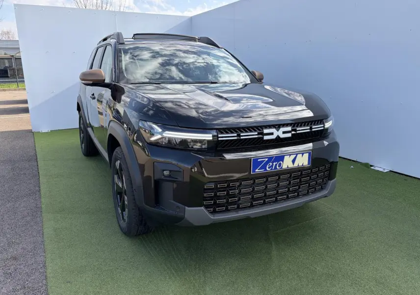 Vue 3/4 avant du Dacia Bigster noir nacré avec calandre brun cuivré et toit panoramique ouvrant.