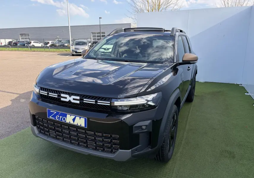 Dacia Bigster noir nacré en 3/4 avant droit avec calandre et rétroviseurs brun cuivré, toit panoramique ouvert.