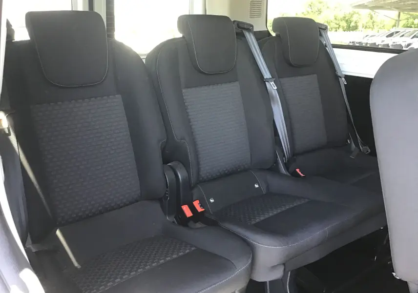 Banquette arrière noire en tissu du Ford Transit Custom Kombi, vue intérieure montrant trois sièges avec ceintures de sécurité.