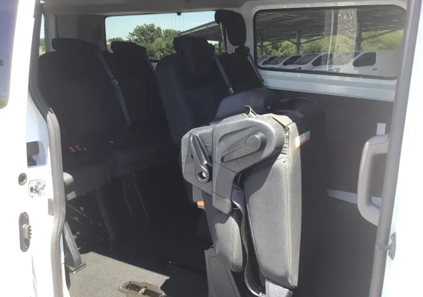 Vue intérieure latérale droite du Ford Transit Custom Kombi blanc 2023, montrant les sièges arrière dont une banquette rabattue.
