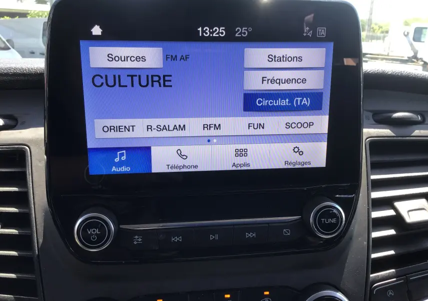 Écran tactile central du Ford Transit Custom Kombi 2023 affichant les options audio et radio, entouré de commandes noires.