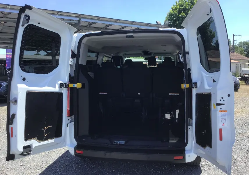 Vue arrière du Ford Transit Custom Kombi blanc 2023 avec portes ouvertes, montrant la banquette arrière et l’espace intérieur.