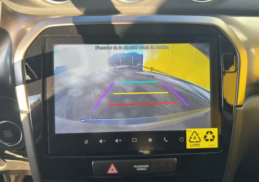 Écran multimédia 9 pouces affichant la caméra de recul du Suzuki Vitara 2025, intérieur noir avec bouton start/stop visible.