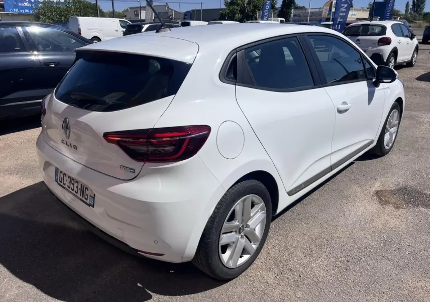 Renault Clio blanc quartz vue 3/4 arrière droit avec becquet et feux arrière LED visibles.