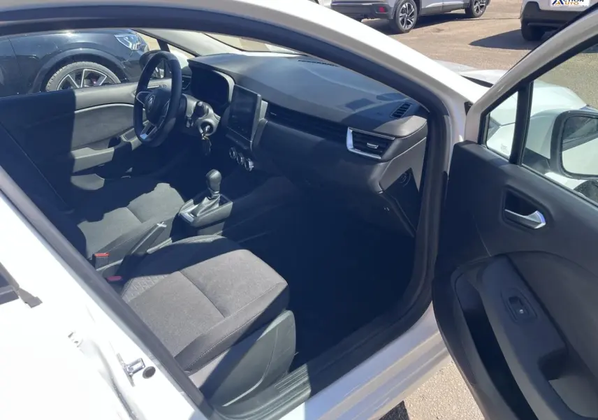 Vue intérieure côté conducteur de la Renault Clio blanc Quartz, montrant sièges noirs et tableau de bord moderne.