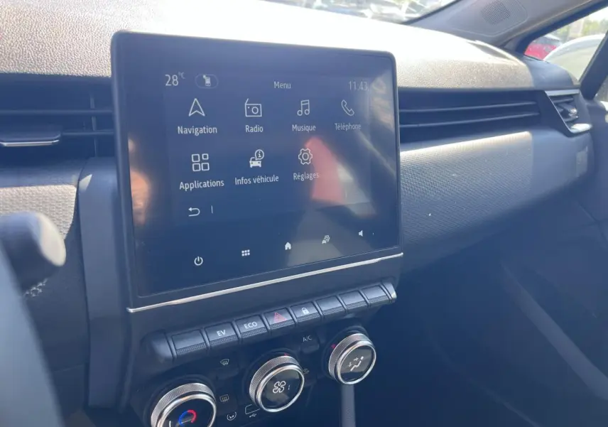 Vue intérieure du tableau de bord de la Renault Clio 1.6 E-Tech 2021, écran tactile et commandes de climatisation visibles.