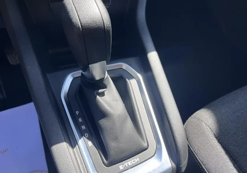 Gros plan sur le levier de vitesses automatique noir avec marquage E-TECH dans l’habitacle d’une Renault Clio blanche.