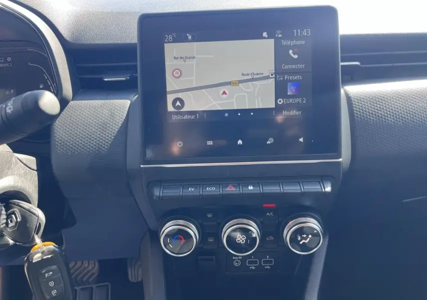 Tableau de bord de Renault Clio 1.6 E-Tech 2021 avec écran tactile GPS et commandes climatisation manuelle en vue frontale.